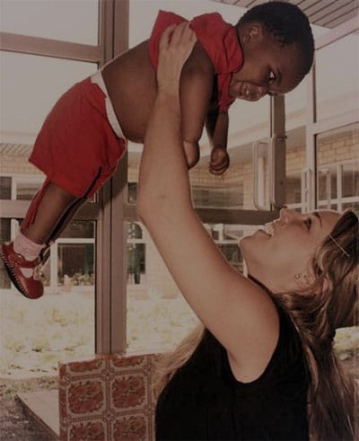 Side shot of Lisa Rogers lifting up a baby in the air.